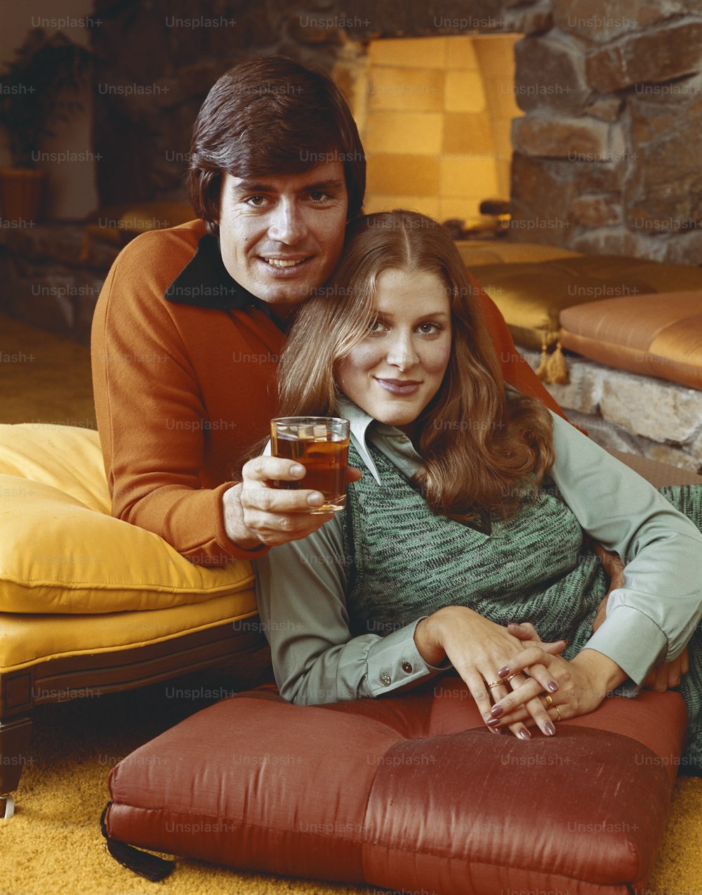 a man and a woman sitting on a couch holding a glass of beer