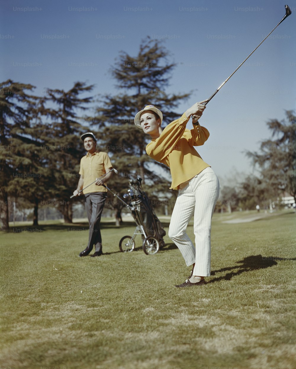 Un hombre balanceando un palo de golf en un campo