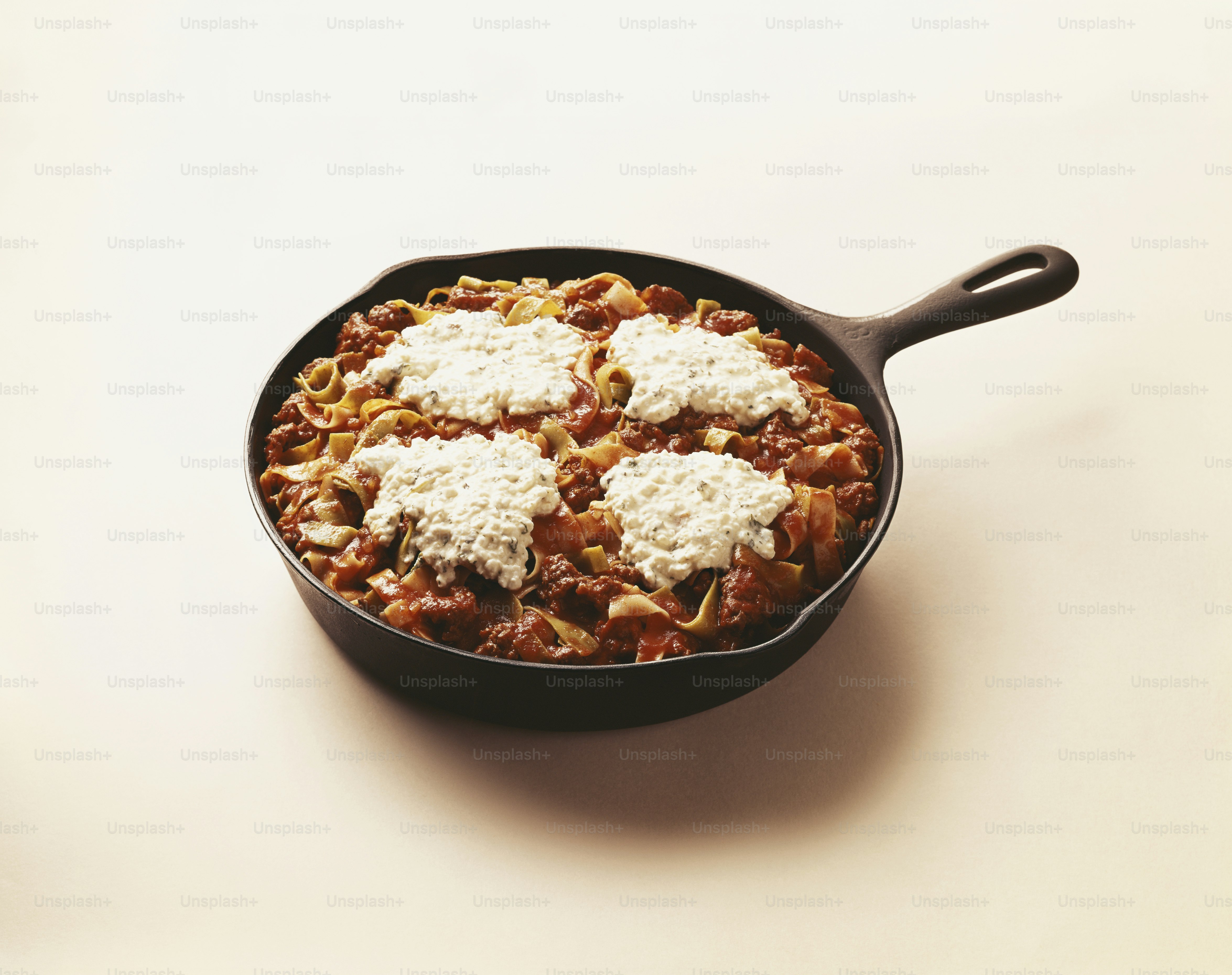 a skillet filled with pasta and cheese on top of a table