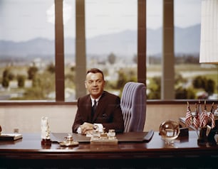 a man sitting at a desk in front of a window