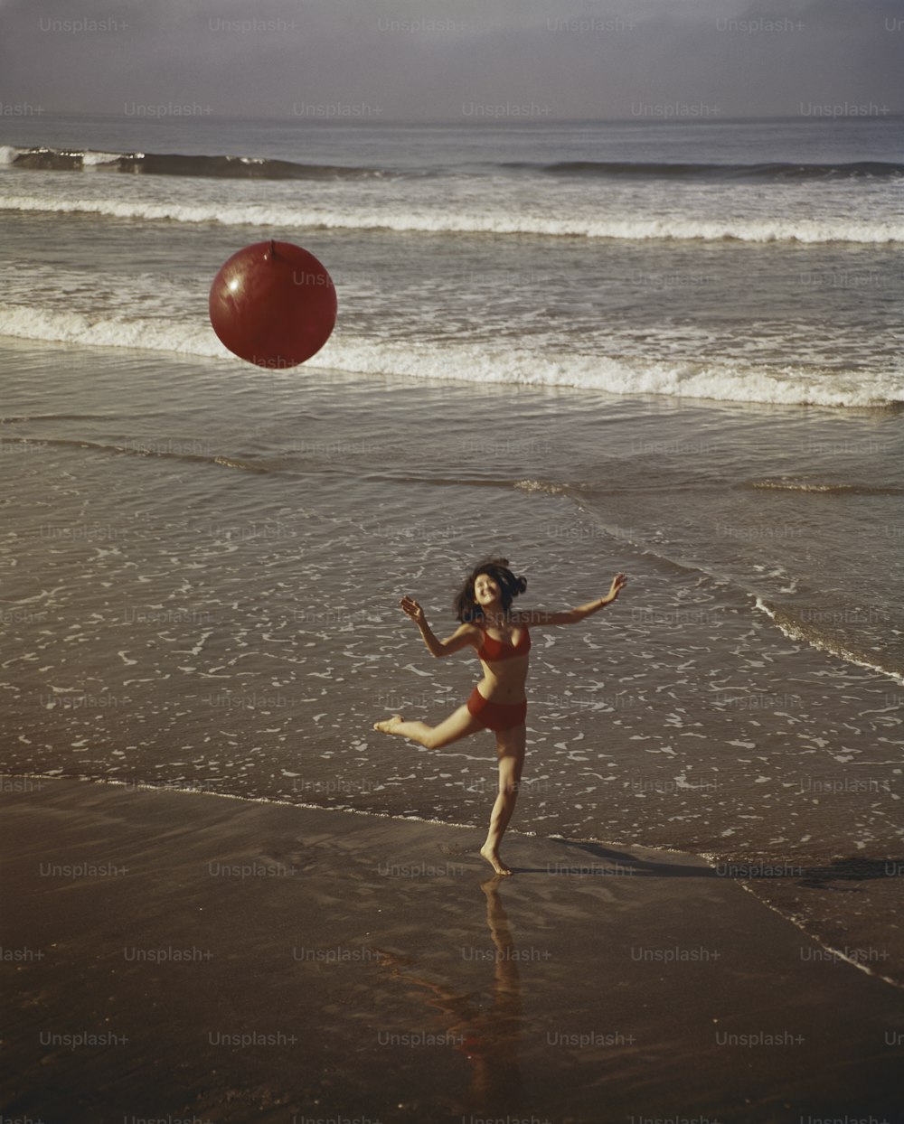 Uma jovem está brincando com uma bola na praia