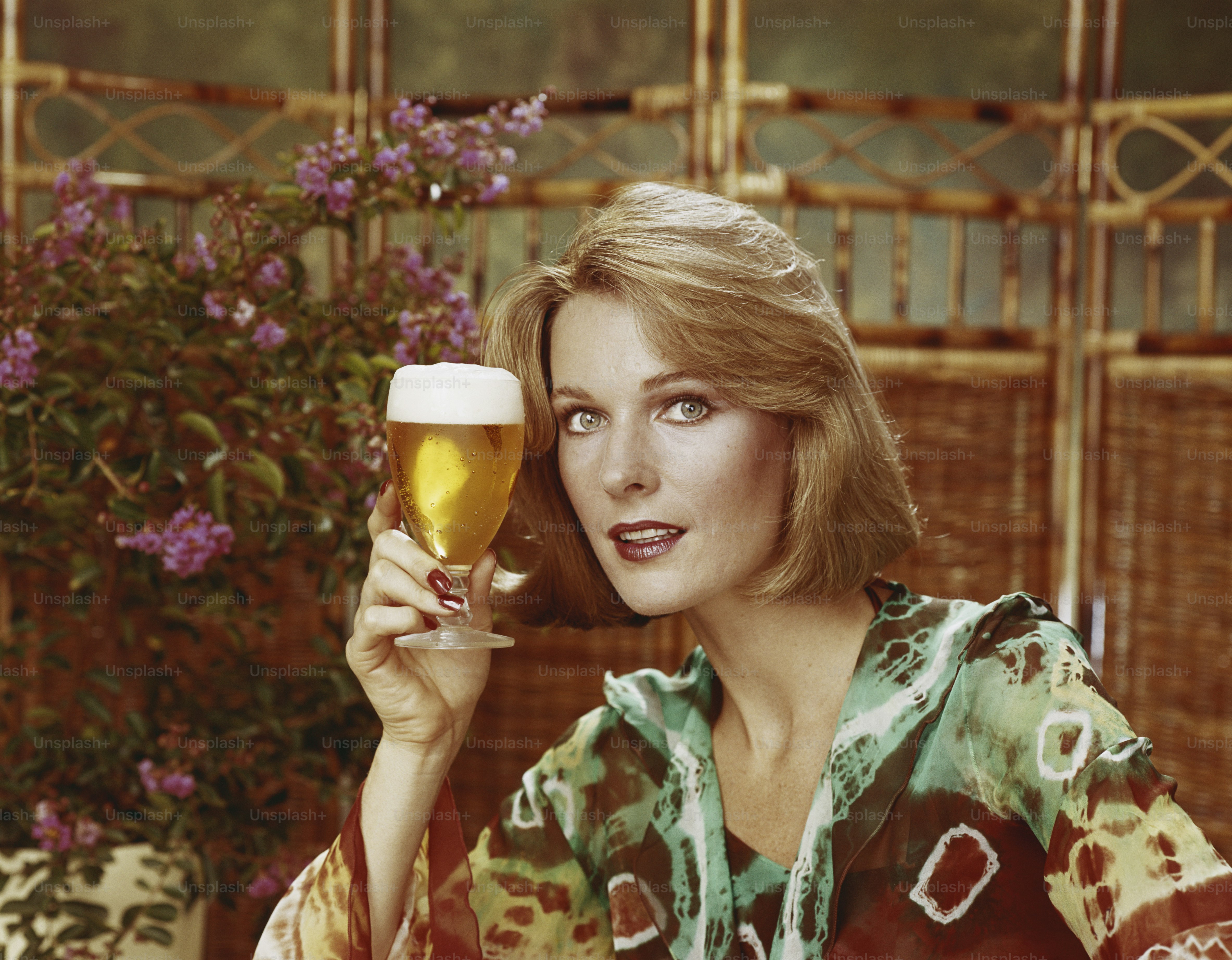 a woman sitting at a table holding a glass of beer