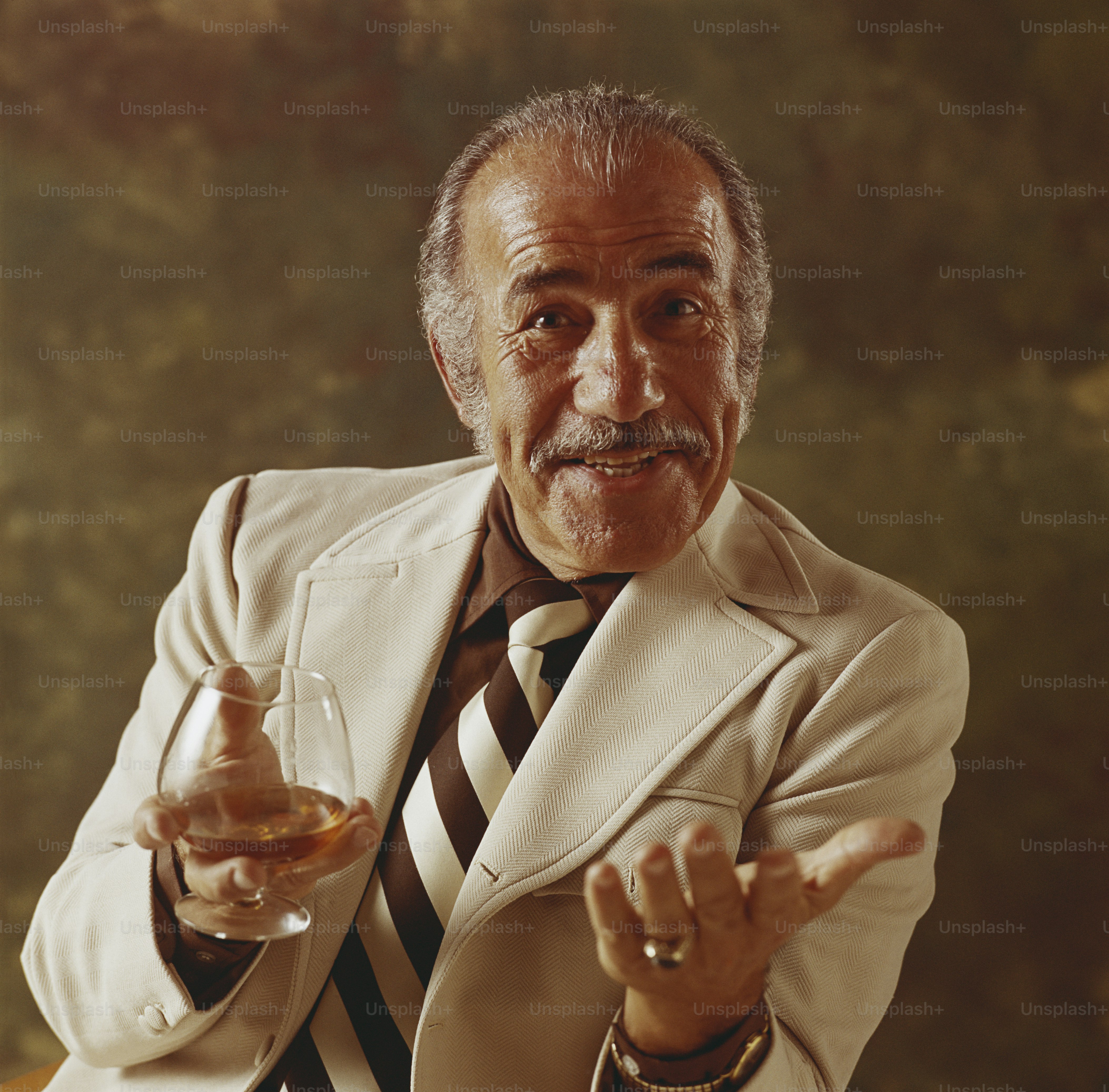 a man in a suit holding a glass of wine