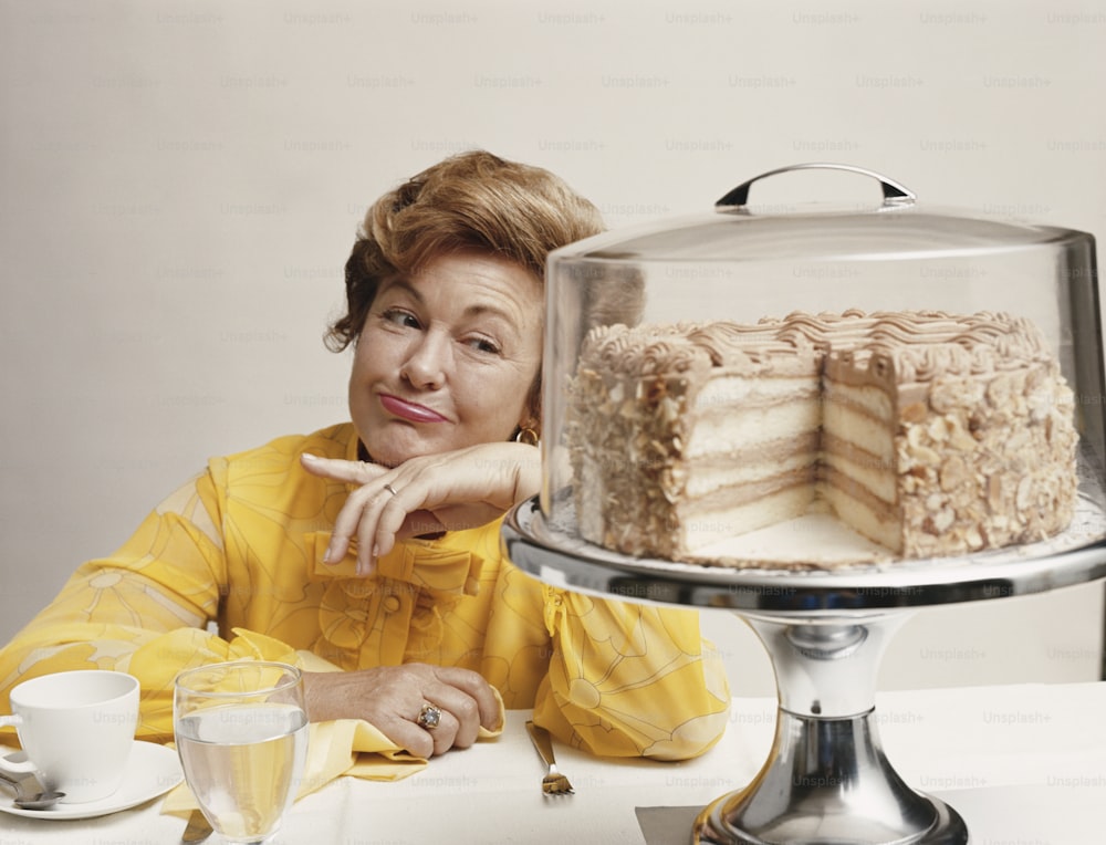 a woman sitting in front of a cake on a table