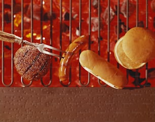 hot dogs, hamburgers, and buns on a grill