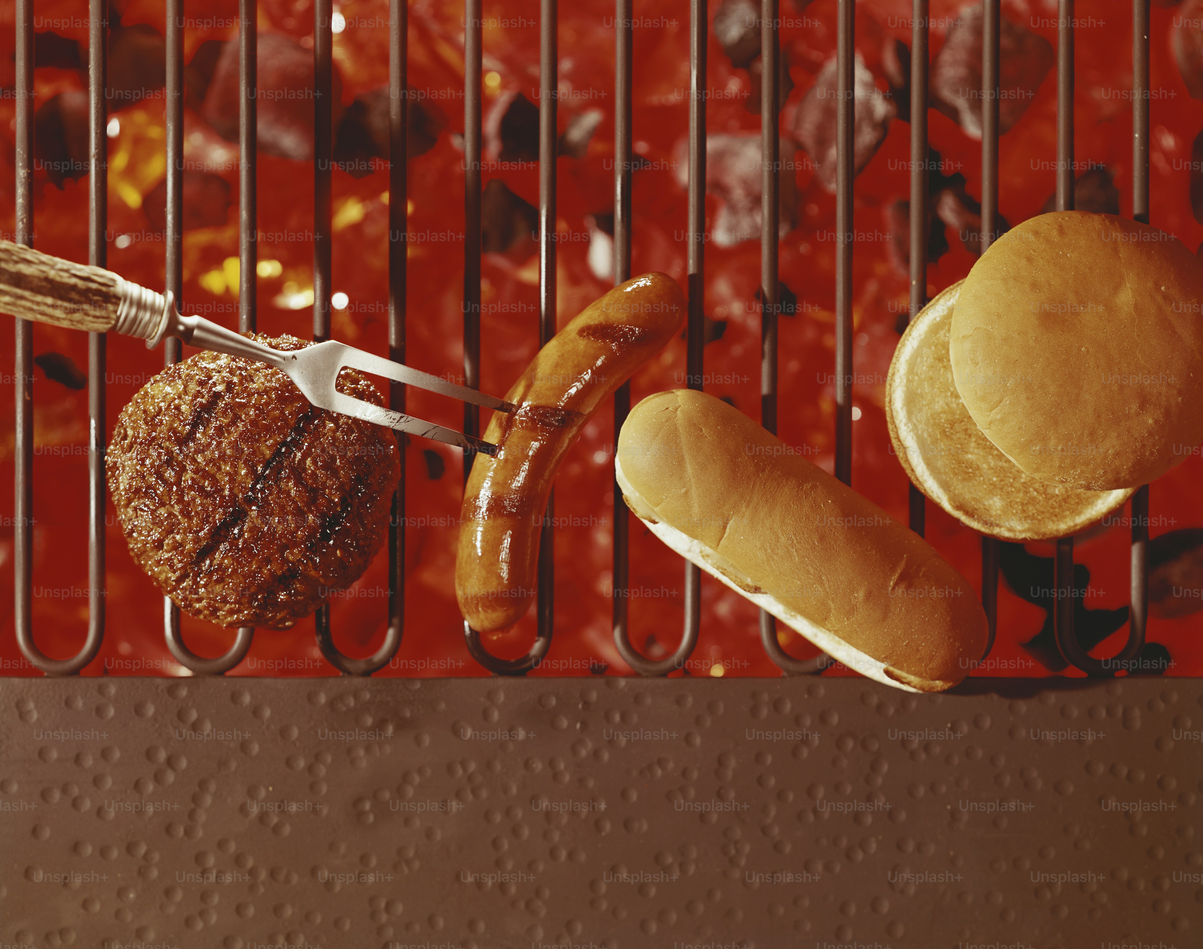 hot dogs, hamburgers, and buns on a grill