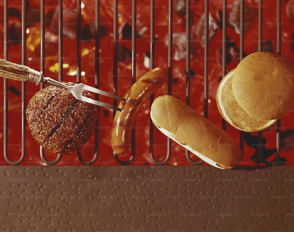 hot dogs, hamburgers, and buns on a grill