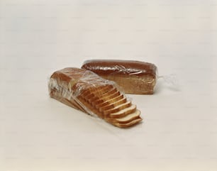 ein Laib Brot und ein Stück Brot, das in Plastik eingewickelt ist