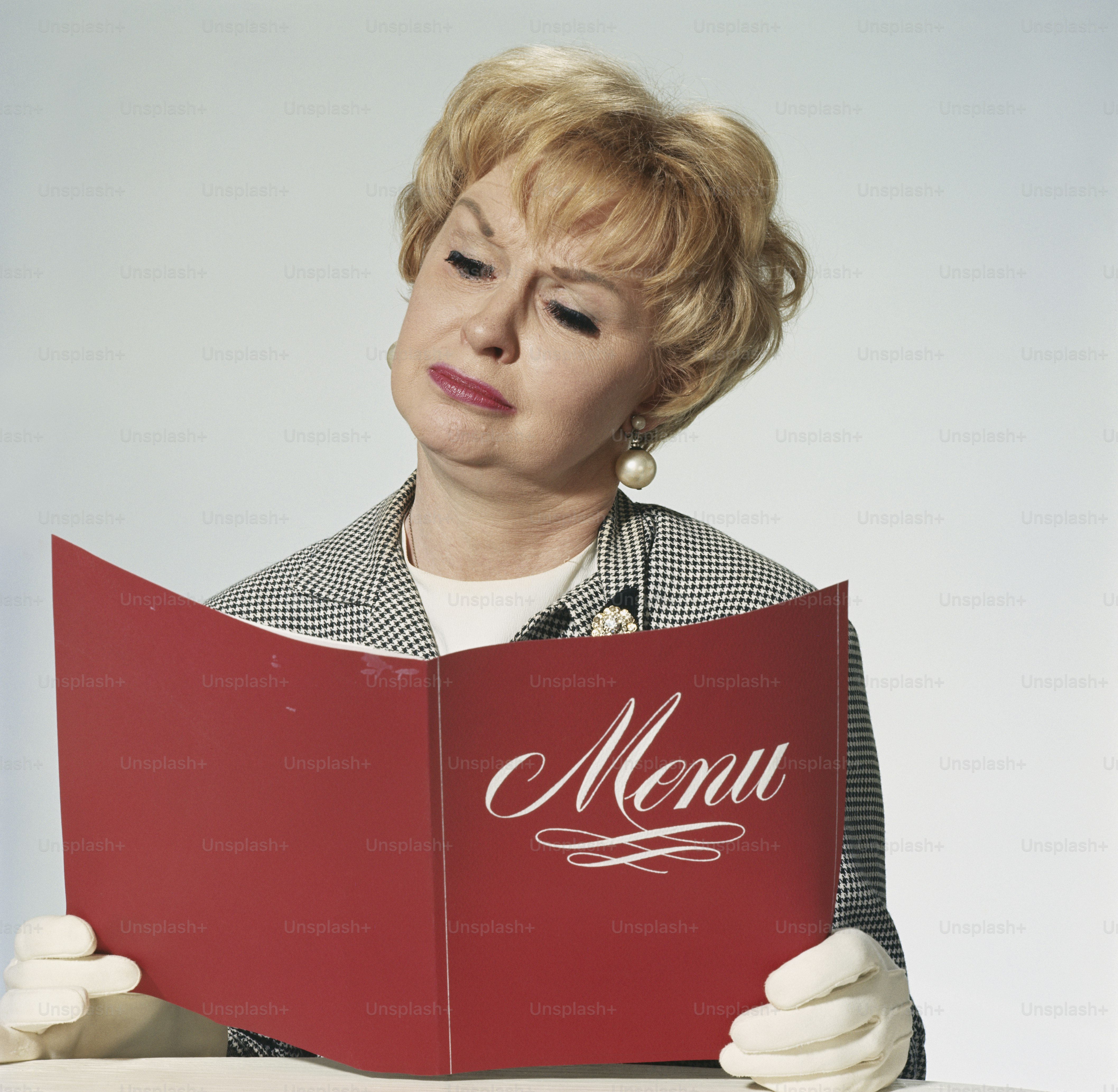Una mujer sentada en una mesa leyendo un menú