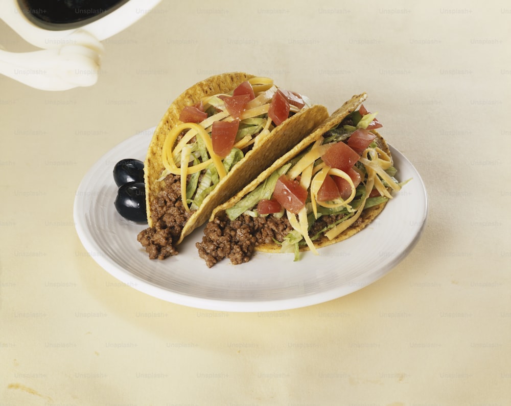 two tacos on a plate with a cup of coffee