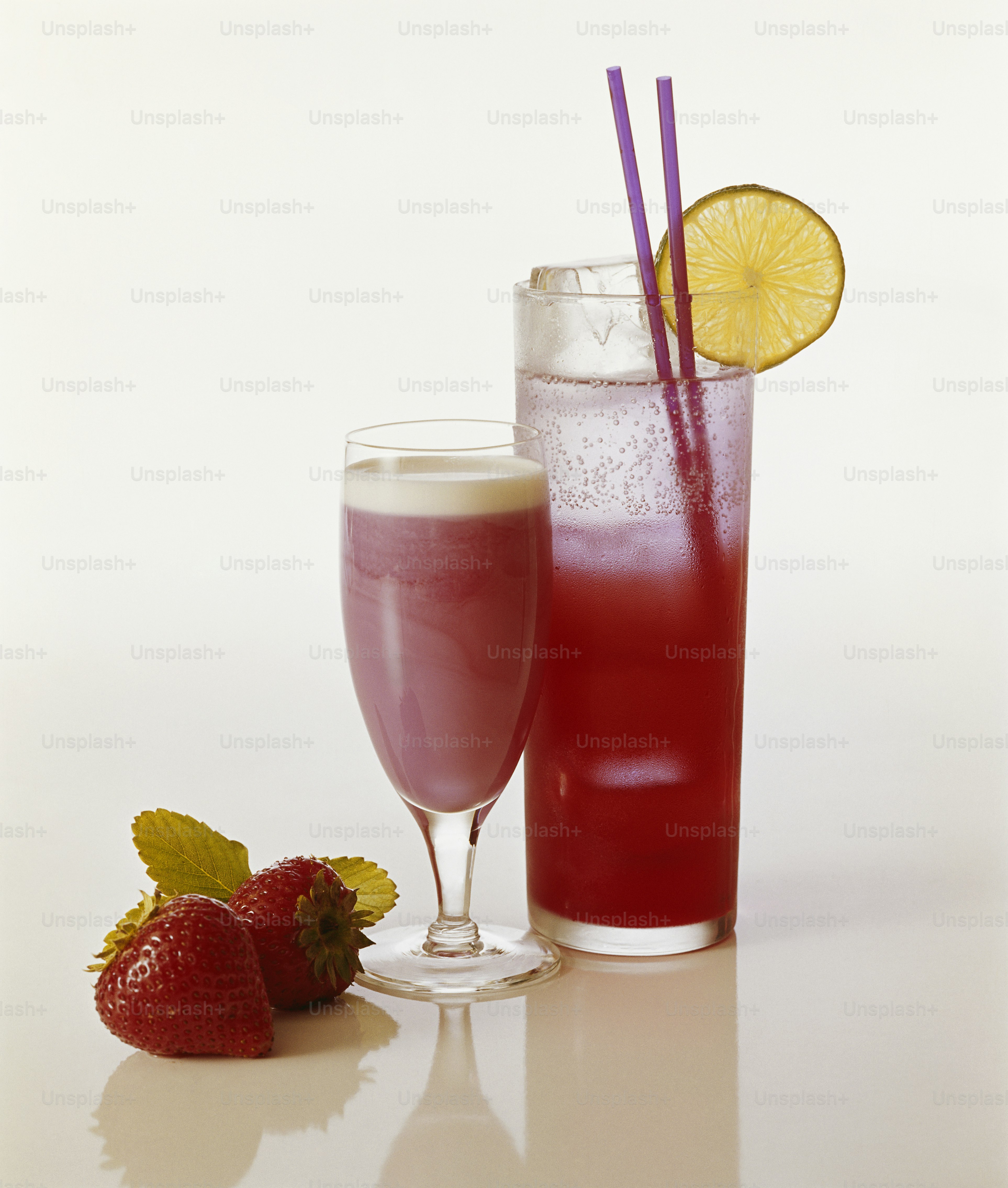 zwei Gläser gefüllt mit Flüssigkeit neben Erdbeeren