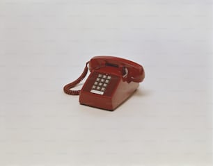 un telefono rosso seduto sopra un tavolo bianco