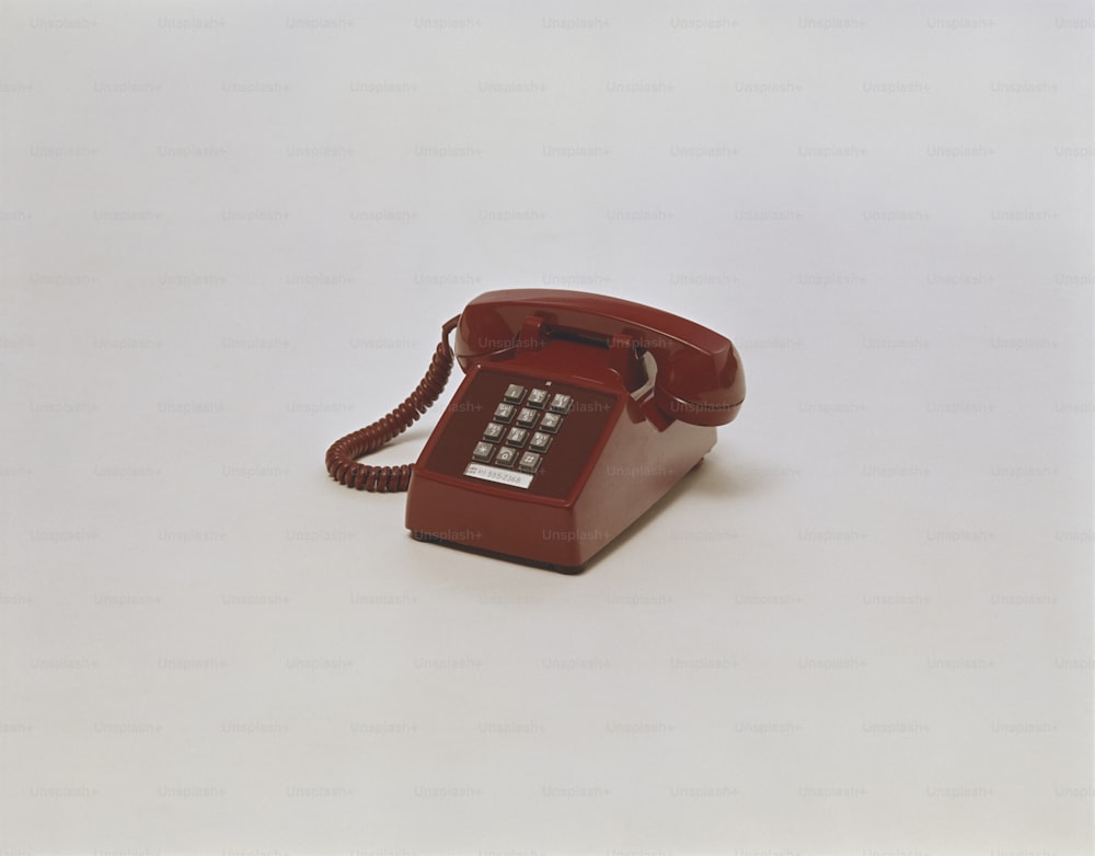 um telefone vermelho sentado em cima de uma mesa branca