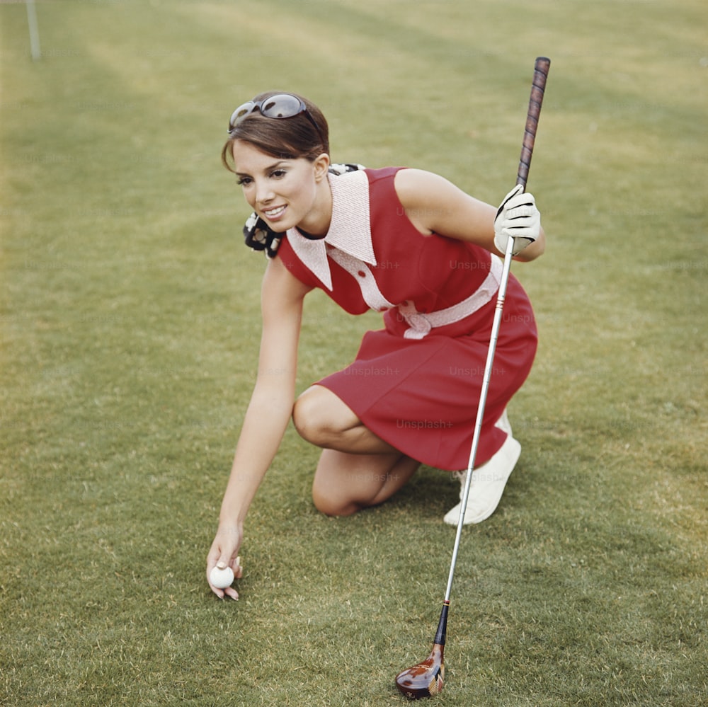 uma mulher em um vestido vermelho segurando um taco de golfe