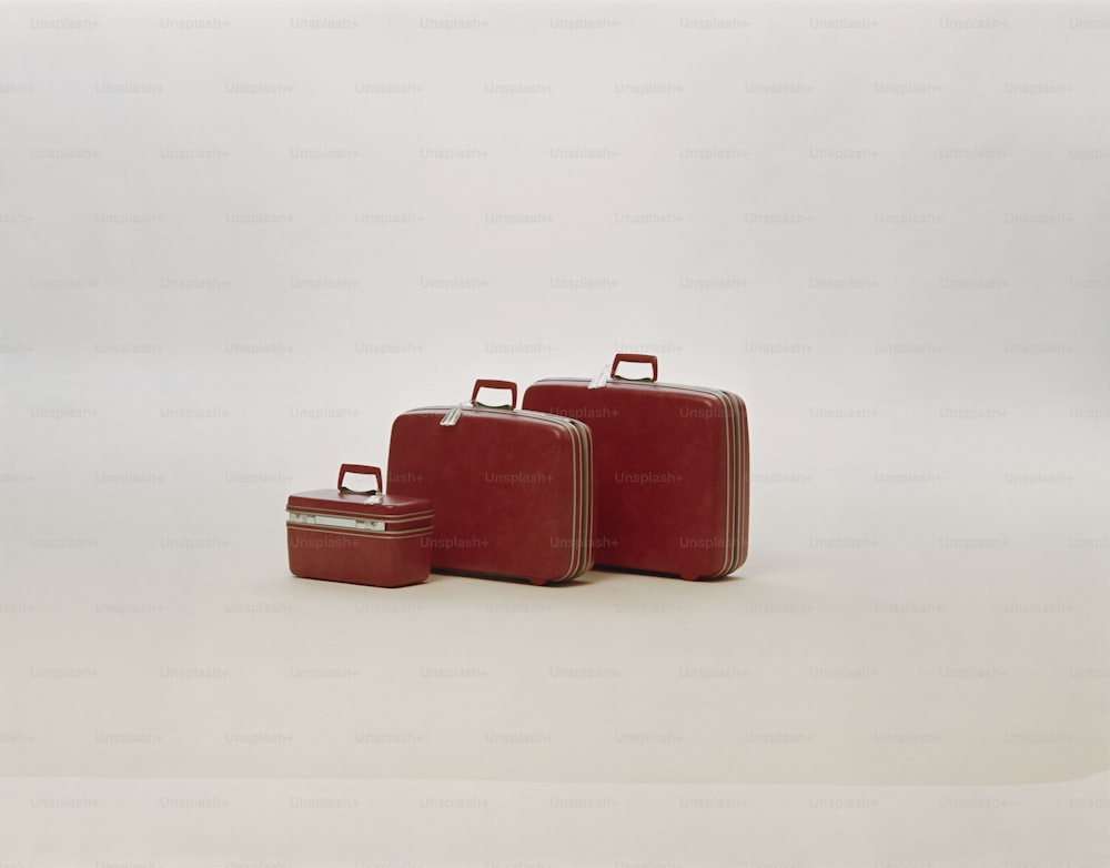 Tres piezas de equipaje rojo sentadas una al lado de la otra