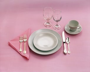 un juego de mesa con cubiertos y un mantel individual rosa