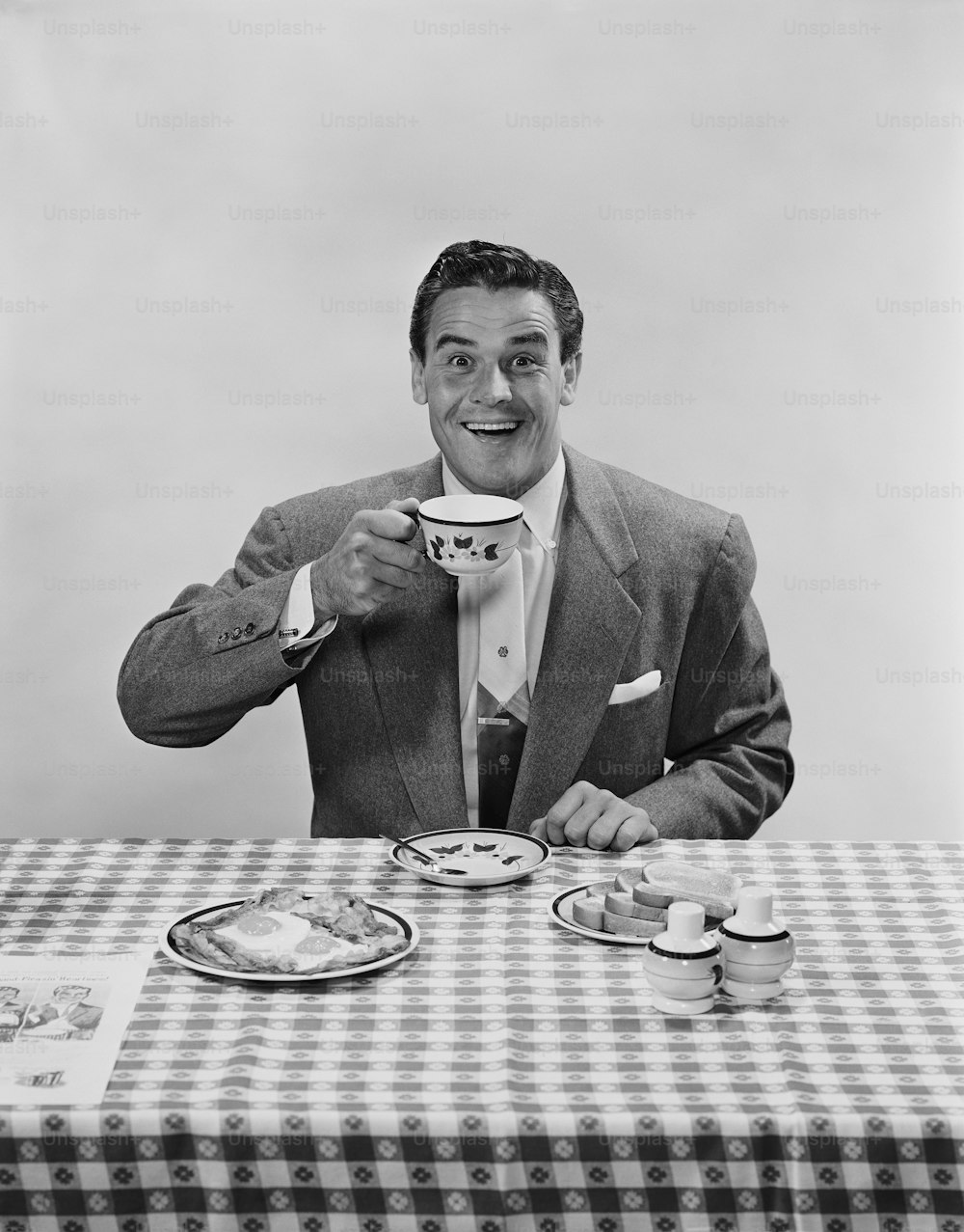 a man sitting at a table drinking a cup of coffee