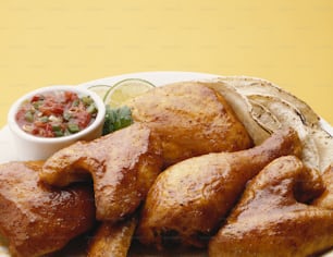 Une assiette blanche garnie d’aliments frits à côté d’un bol de salsa