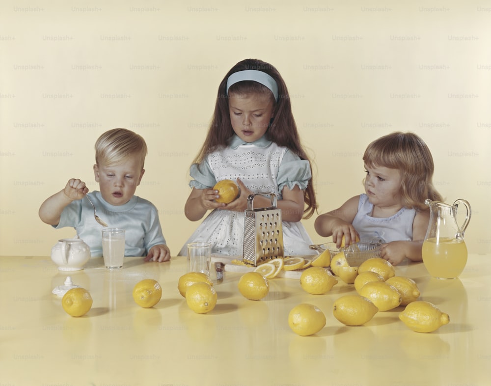 レモンを持ってテーブルに座っている3人の小さな女の子