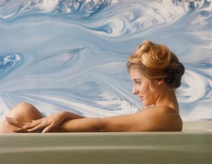 a woman is sitting in a bathtub with her legs crossed