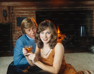 a man and a woman sitting on the floor with a drink