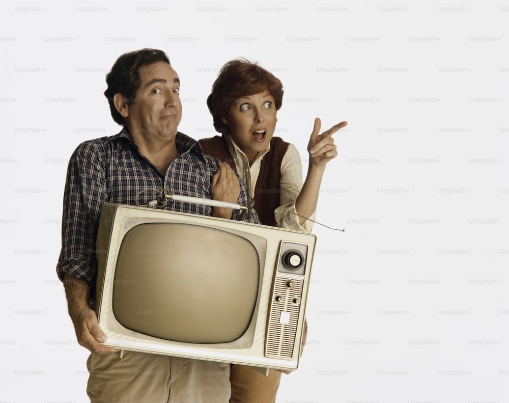 a man and a woman are holding a television