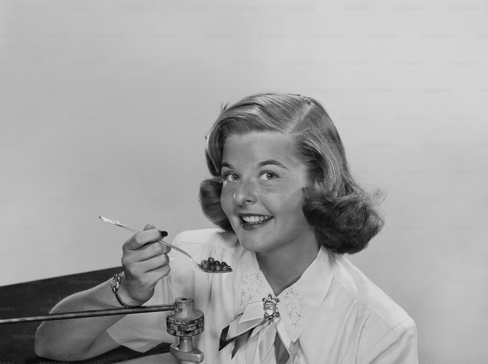 a black and white photo of a woman holding a spoon