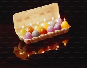 uma dúzia de velas estão em uma caixa sobre uma mesa