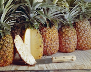 a pineapple cut in half next to a knife