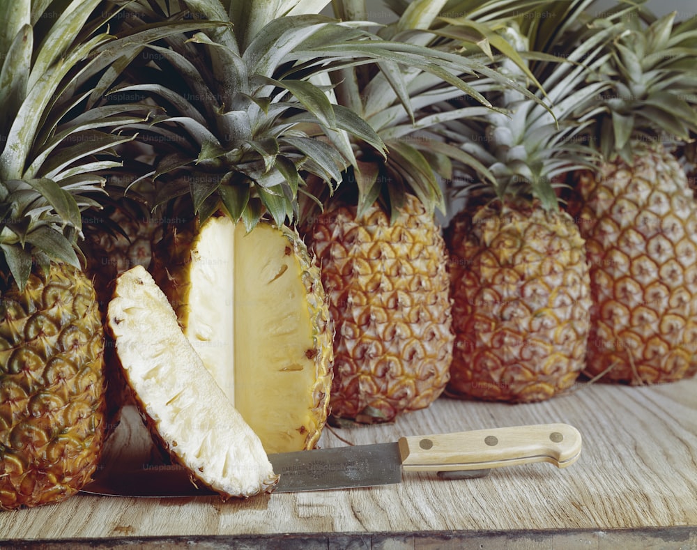 a pineapple cut in half next to a knife