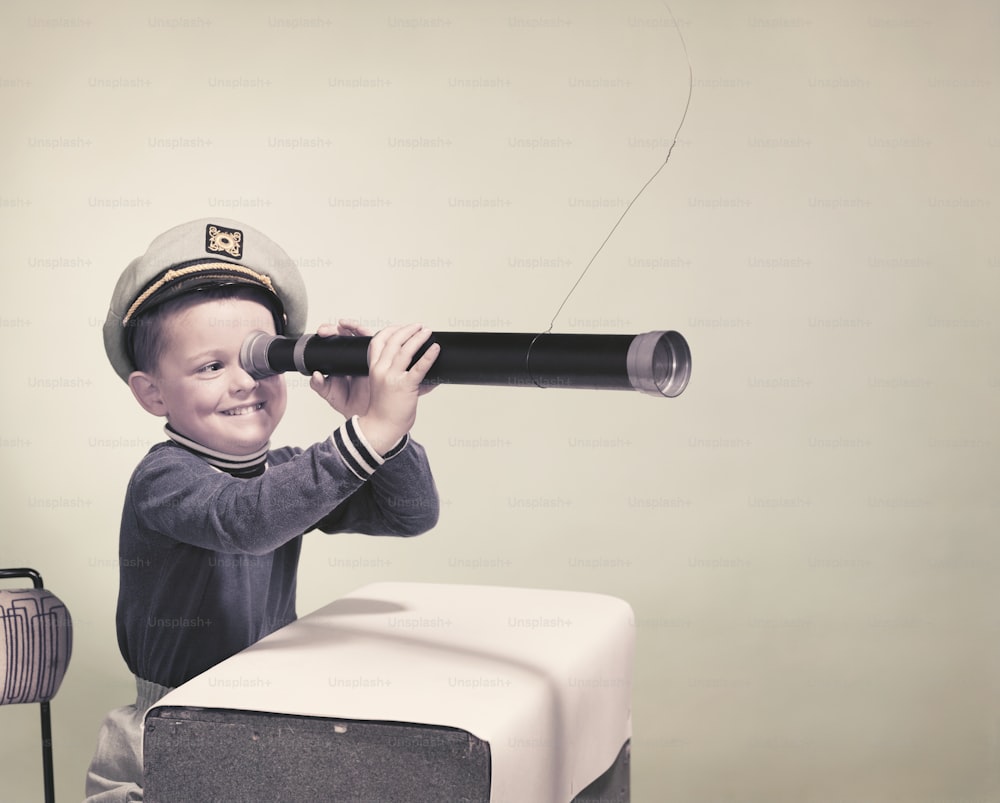 a young boy wearing a hat and holding a telescope