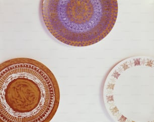 three plates with designs on them sitting on a table