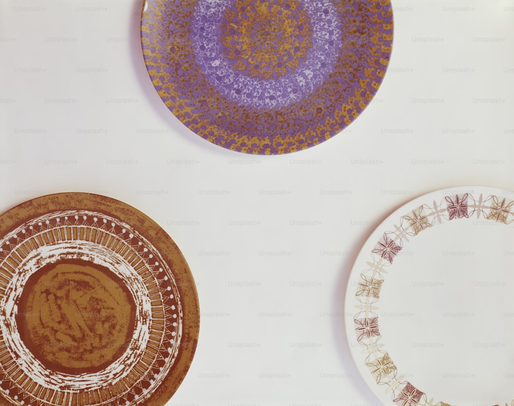 three plates with designs on them sitting on a table