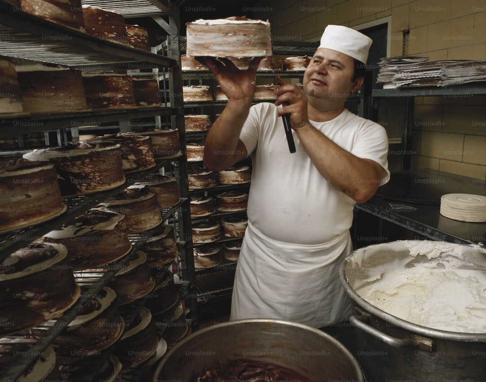 a man holding a cake in front of a rack of baked goods
