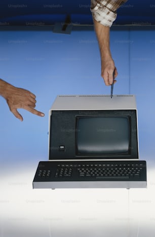 a hand is holding a knife over a computer