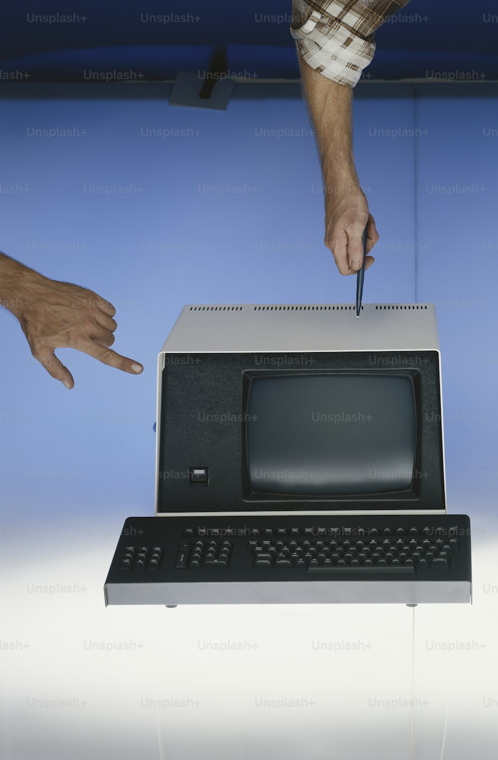 a hand is holding a knife over a computer