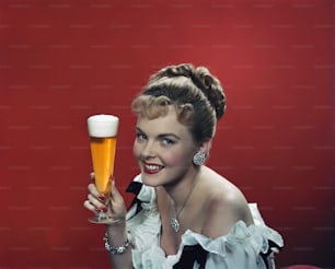 a woman in a white dress holding a glass of beer