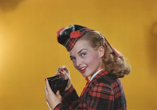 a woman in a red and black plaid jacket holding a black purse