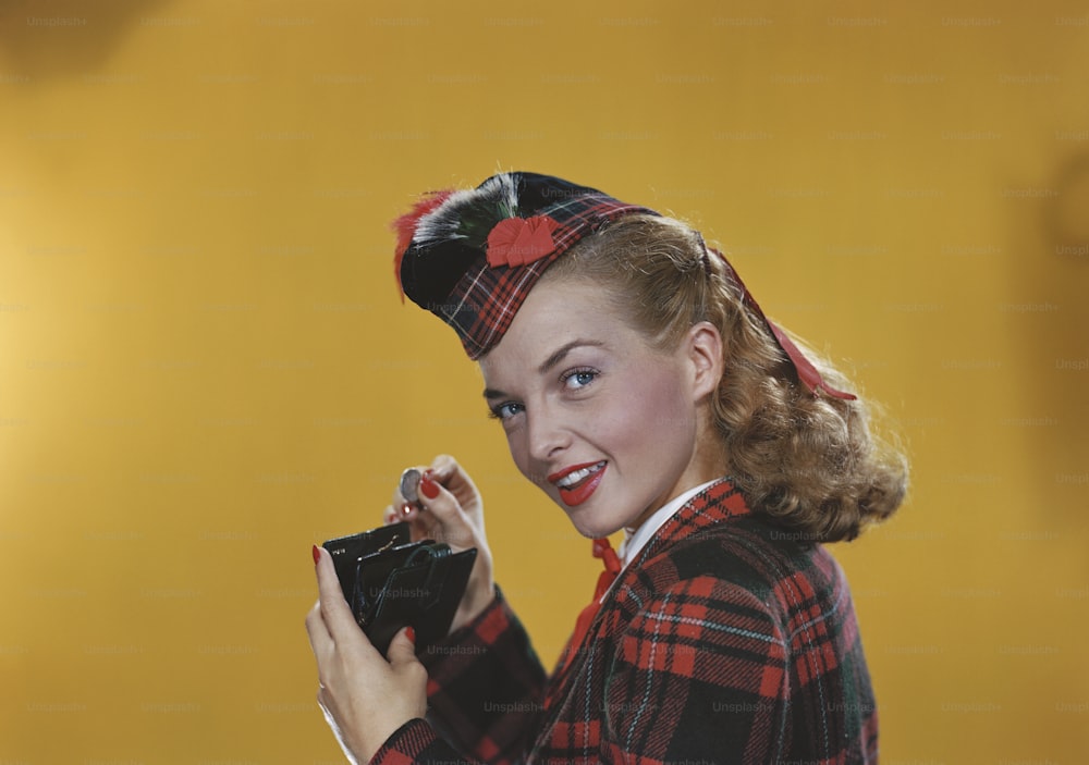 a woman in a red and black plaid jacket holding a black purse