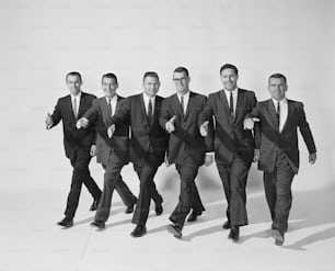 Un grupo de hombres con traje y corbata caminando juntos