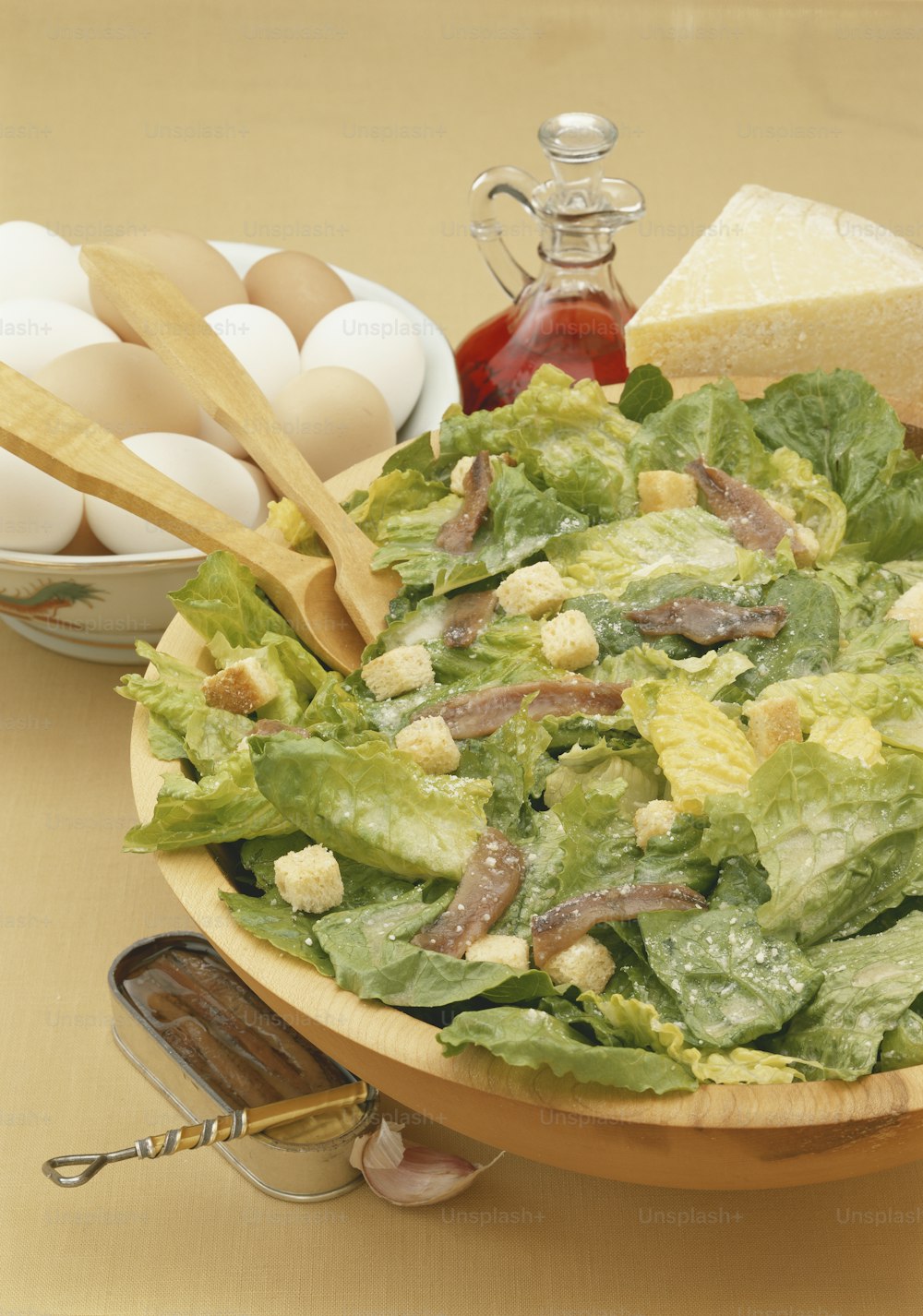 a wooden bowl filled with lettuce next to eggs