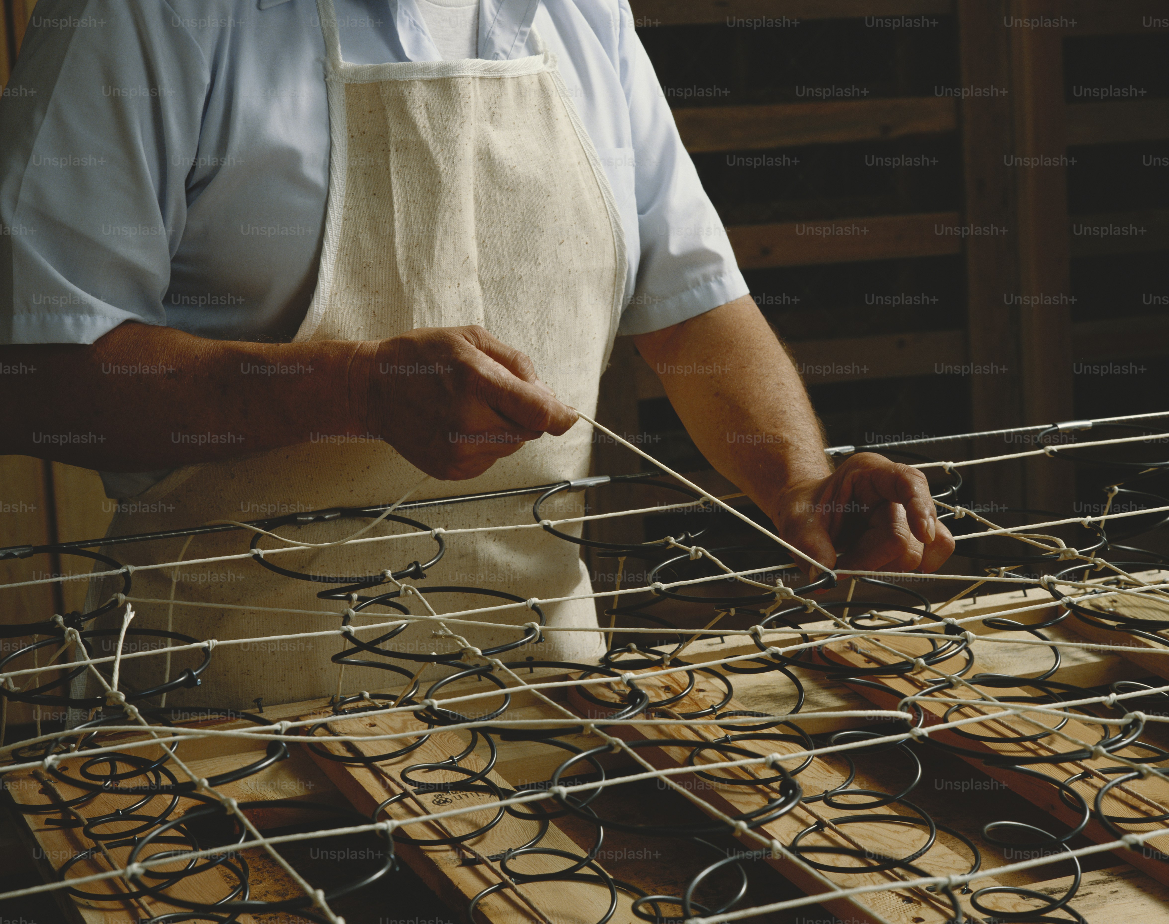 Ein Mann in einer Schürze arbeitet an einem Stück Draht