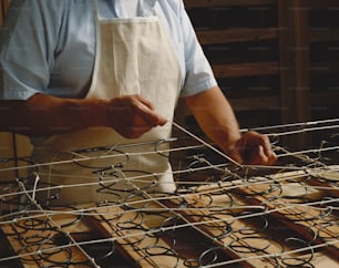 a man in an apron is working on a piece of wire