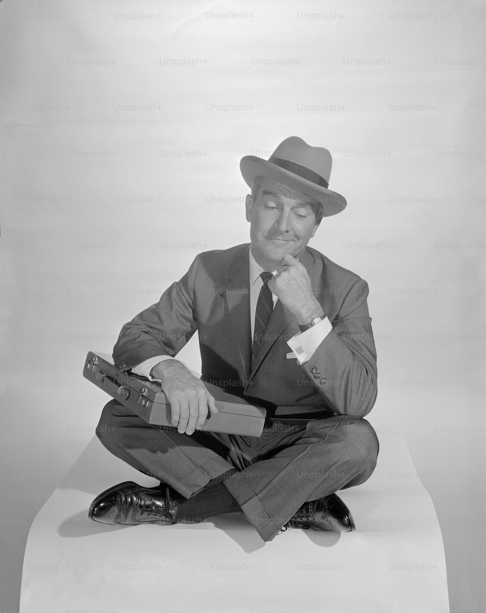 a man in a suit and hat sitting on the ground