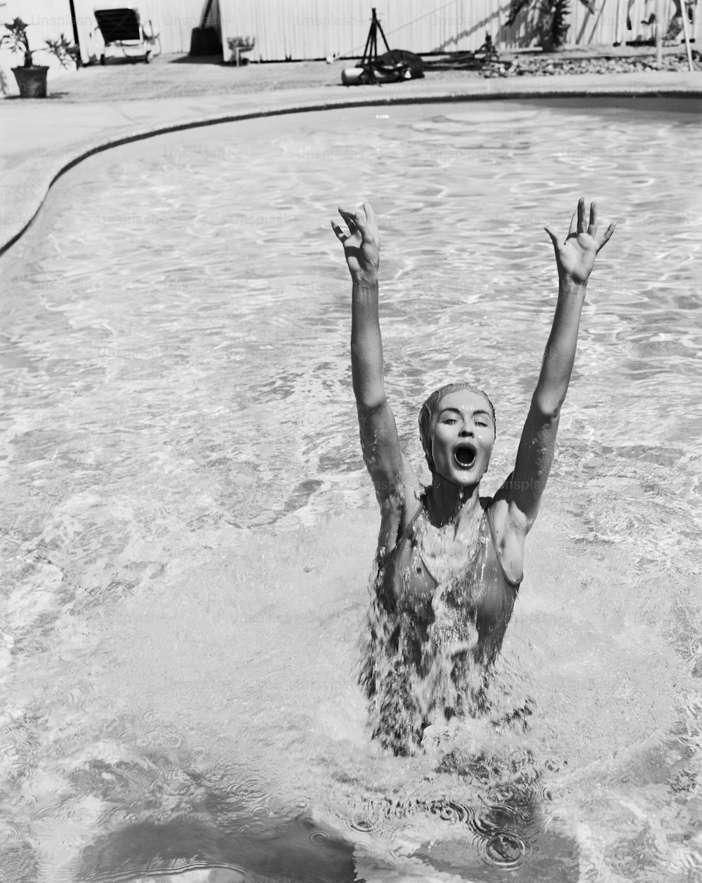 a woman swimming in a pool with her hands up