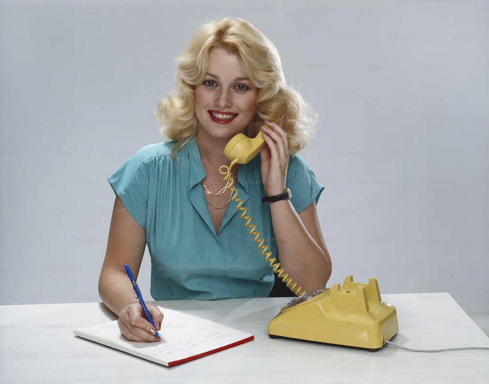 a woman sitting at a desk talking on a phone