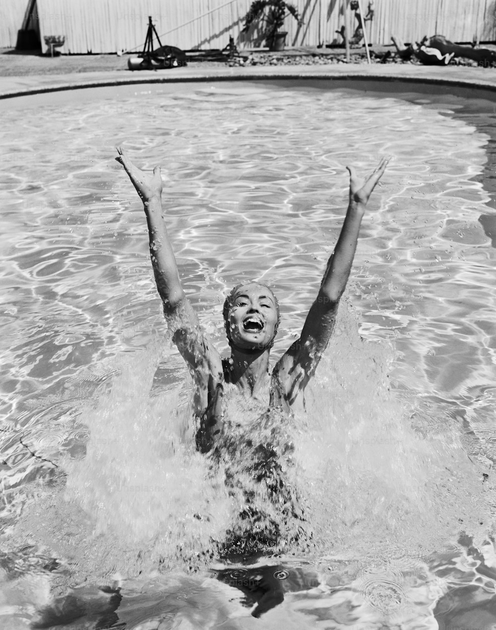 a young boy swimming in a pool with his arms in the air