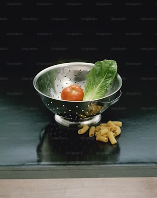 a colander with pasta and a tomato in it