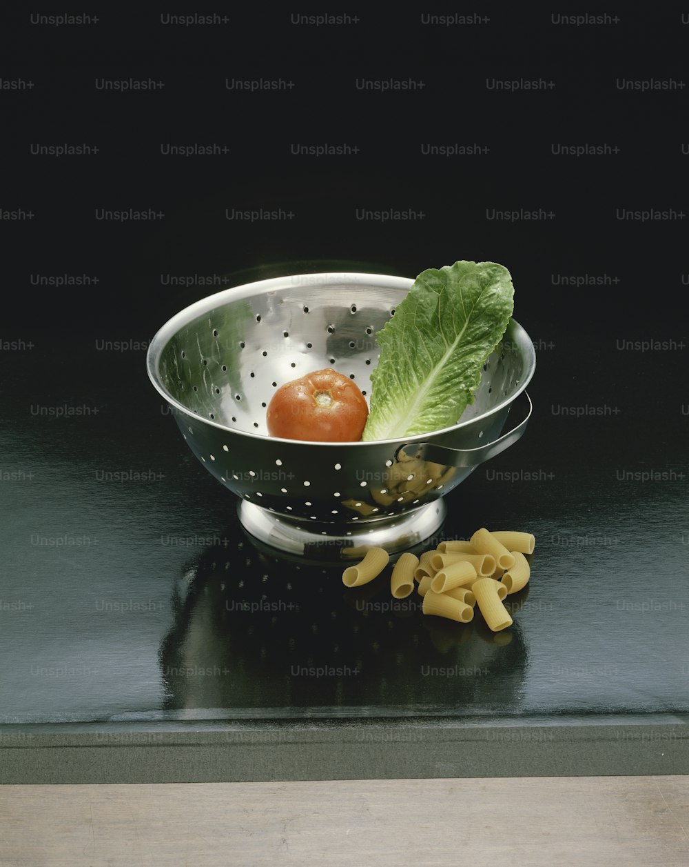 a colander with pasta and a tomato in it