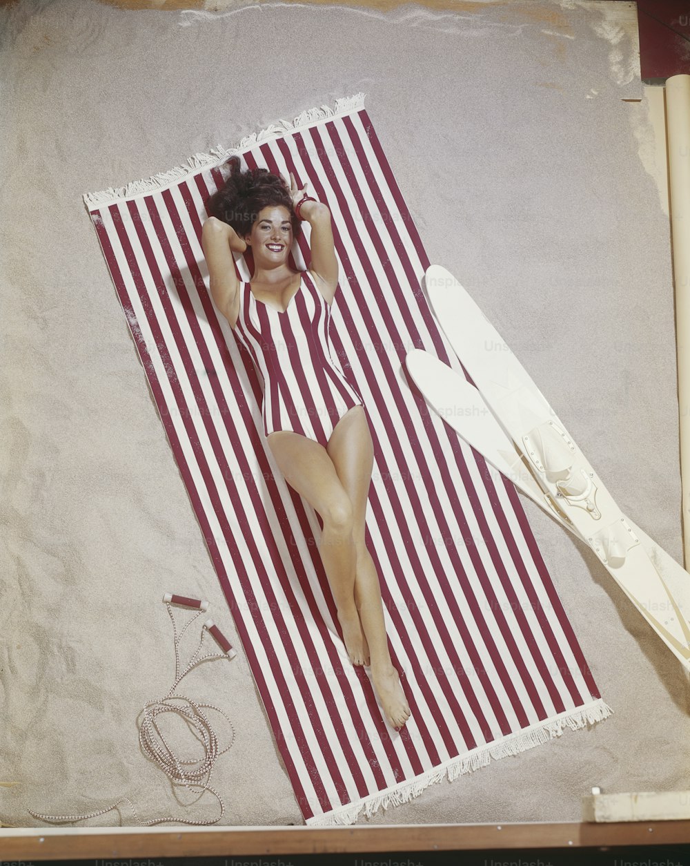uma mulher em um traje de banho deitado em uma toalha de praia
